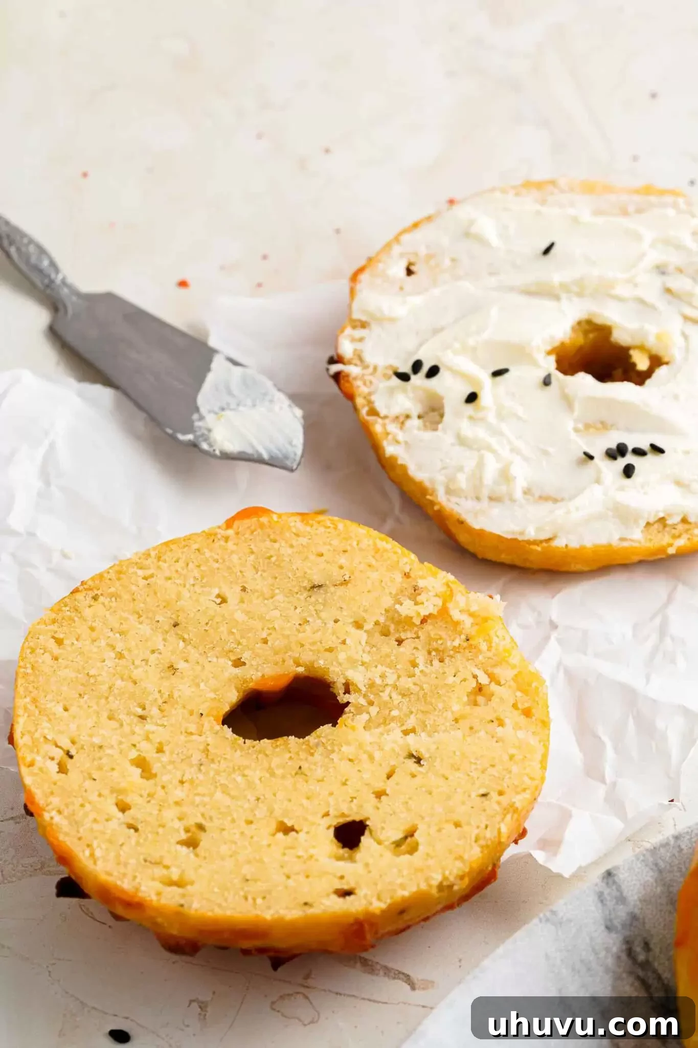A sliced keto cheese bagel, revealing its soft interior, paired with cream cheese for a classic treat.