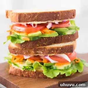 hummus and veggie sandwich on a wooden cutting board