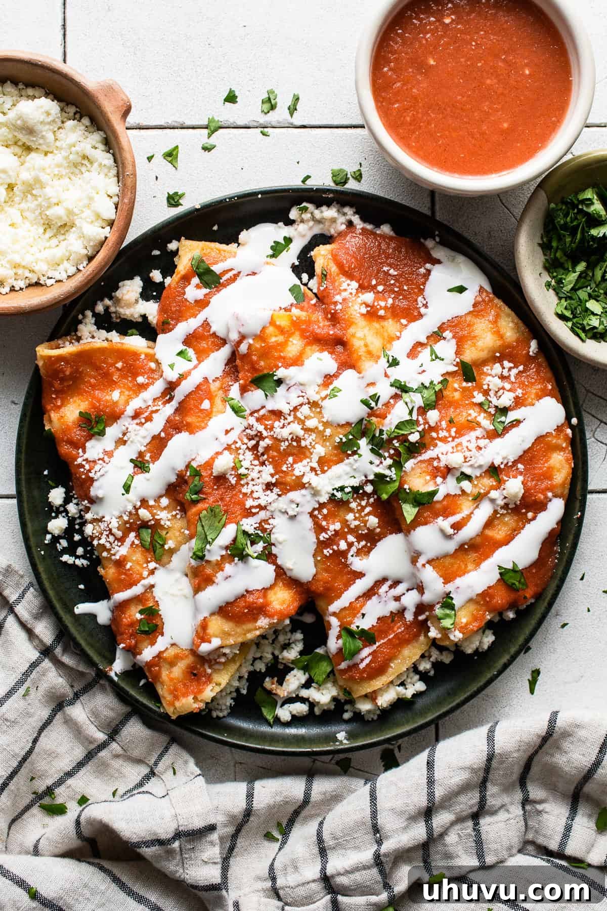 Tomato-Smothered Tortillas 2 Entomatadas on a plate garnished with Mexican crema, cotija cheese, and cilantro, ready to be served.