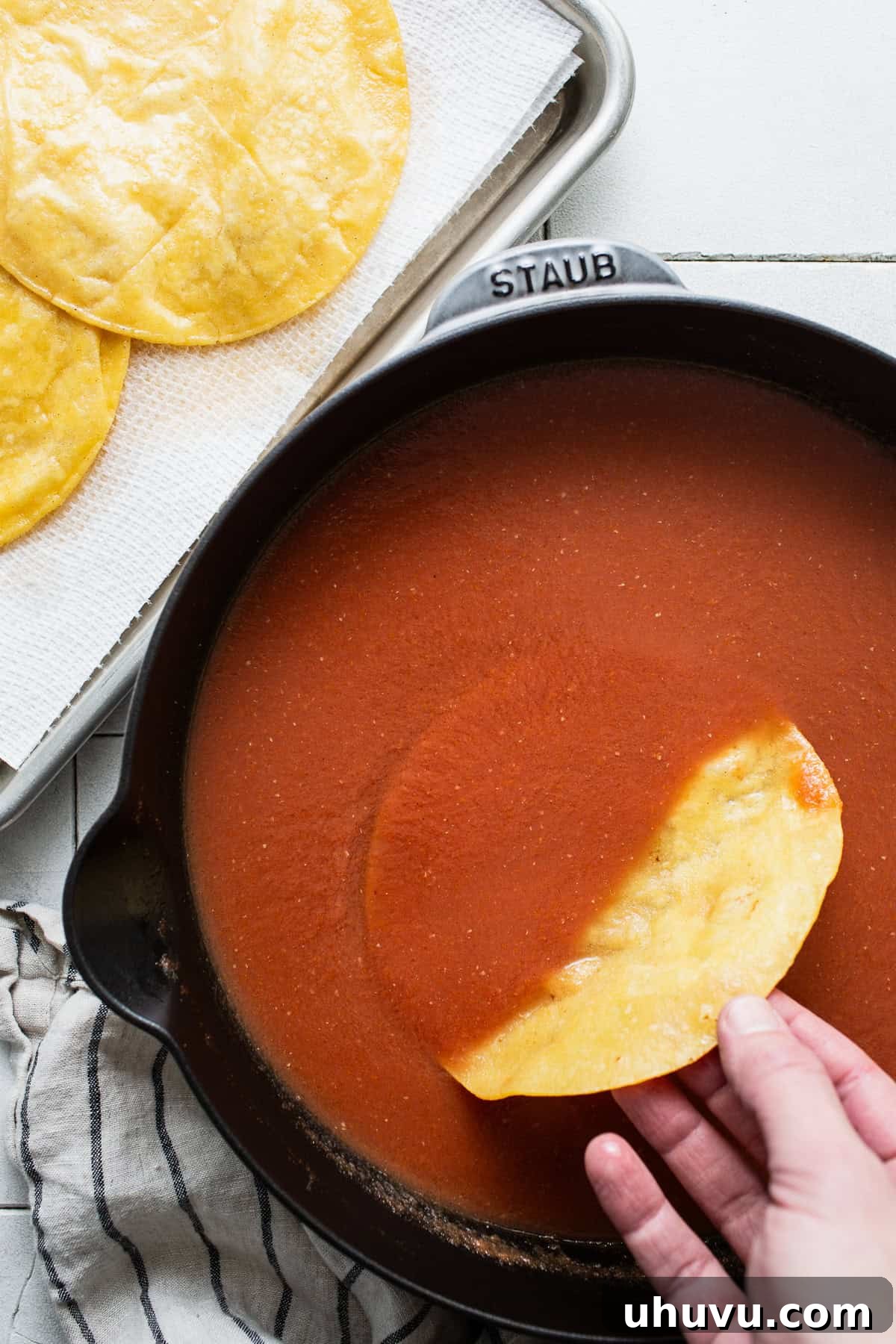 Tomato-Smothered Tortillas 8 A lightly fried corn tortilla being dipped into the entomatada sauce in a skillet.
