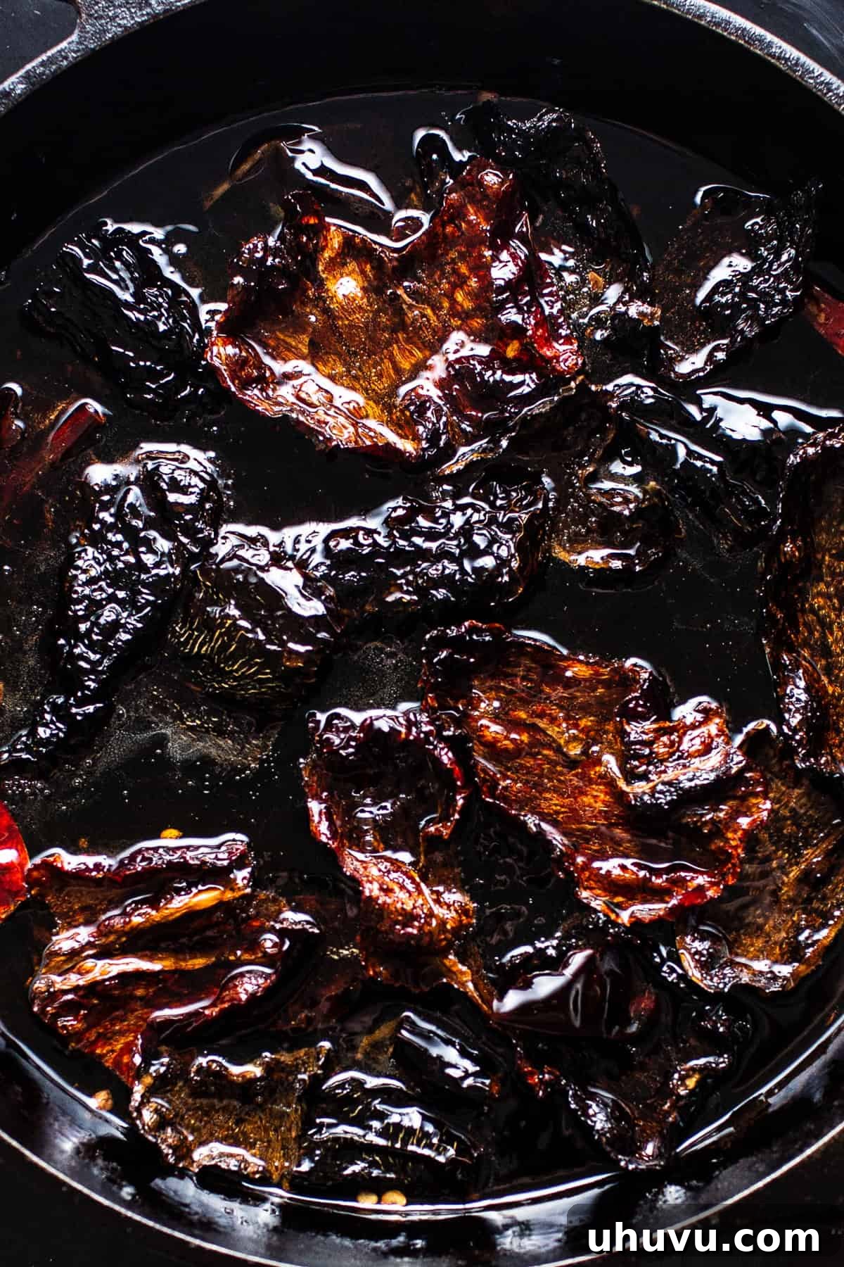 Guajillo, ancho, and árbol chiles gently frying in hot oil
