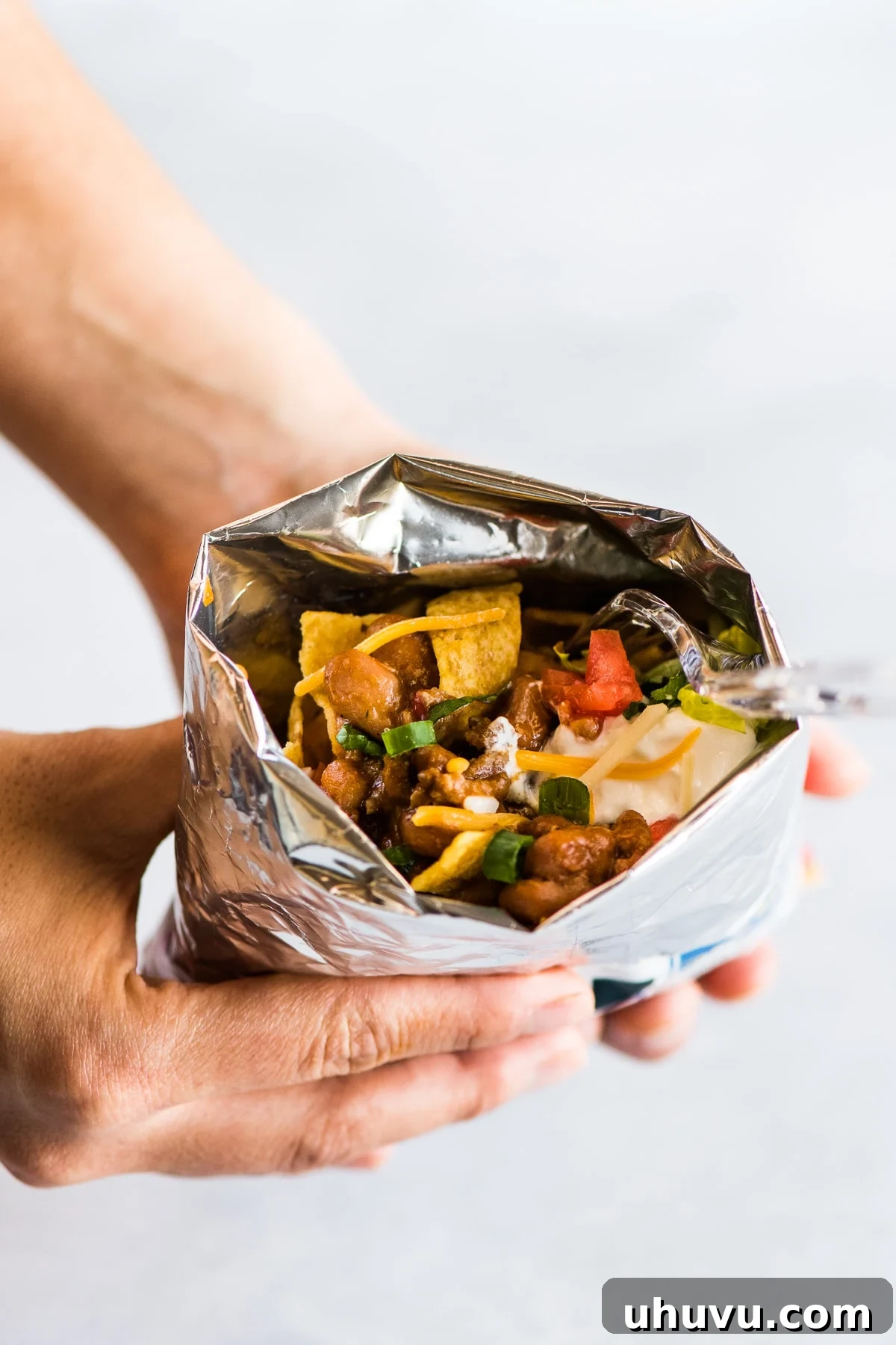 Chip Bag Tacos 7 Two hands holding a bag of walking tacos with a fork, ready to eat.