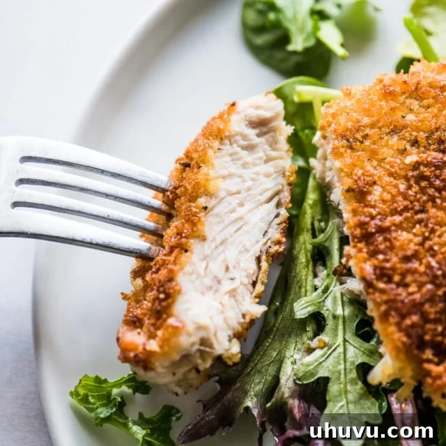 A Milanesa de pollo sliced and ready to eat on a fork.