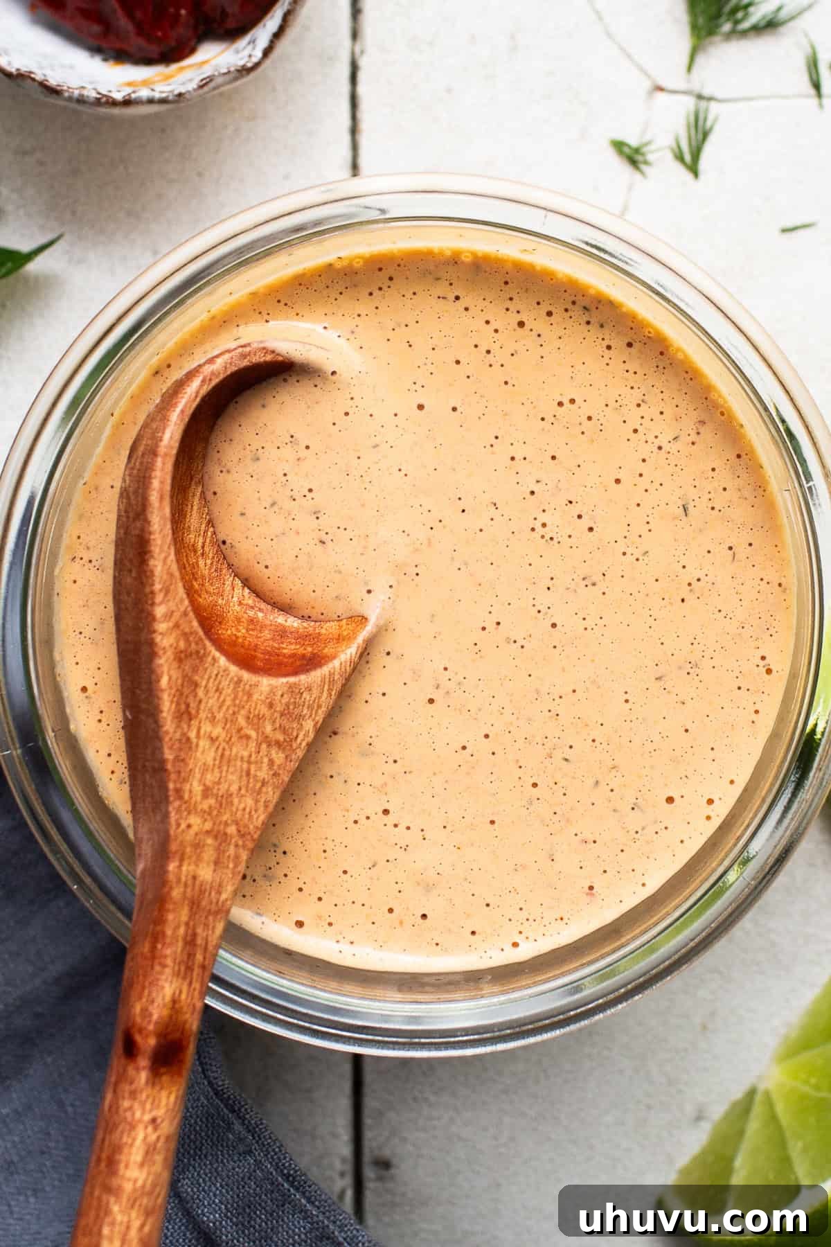 Velvet Heat Ranch 6 A close-up shot of the finished, creamy chipotle ranch dressing in a glass jar, with a wooden spoon dipped into it, highlighting its smooth and rich texture.