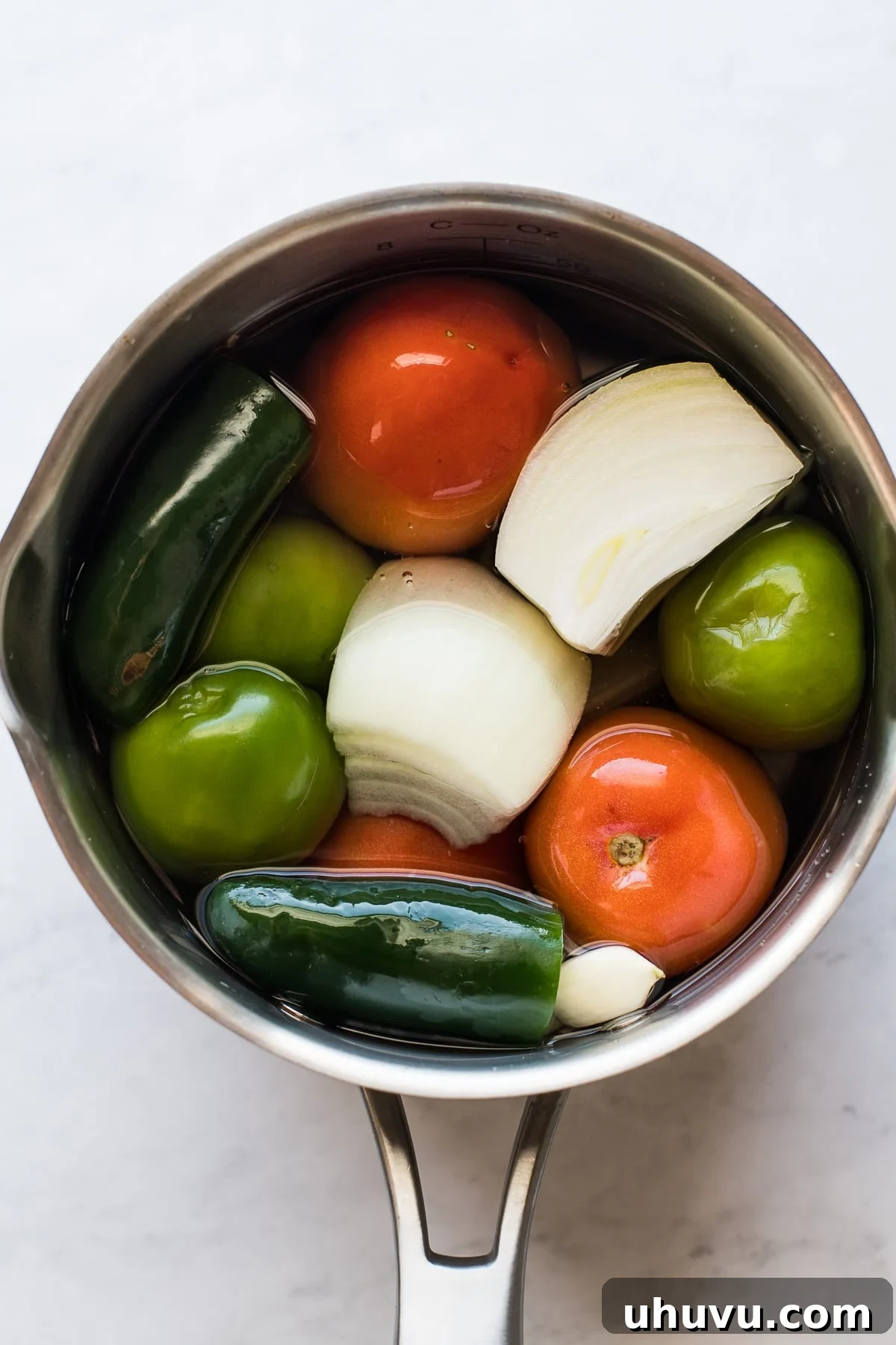 Divorced Eggs 3 Assorted vegetables including Roma tomatoes, tomatillos, yellow onions, and jalapeños simmering in a pot, ready for salsa preparation.