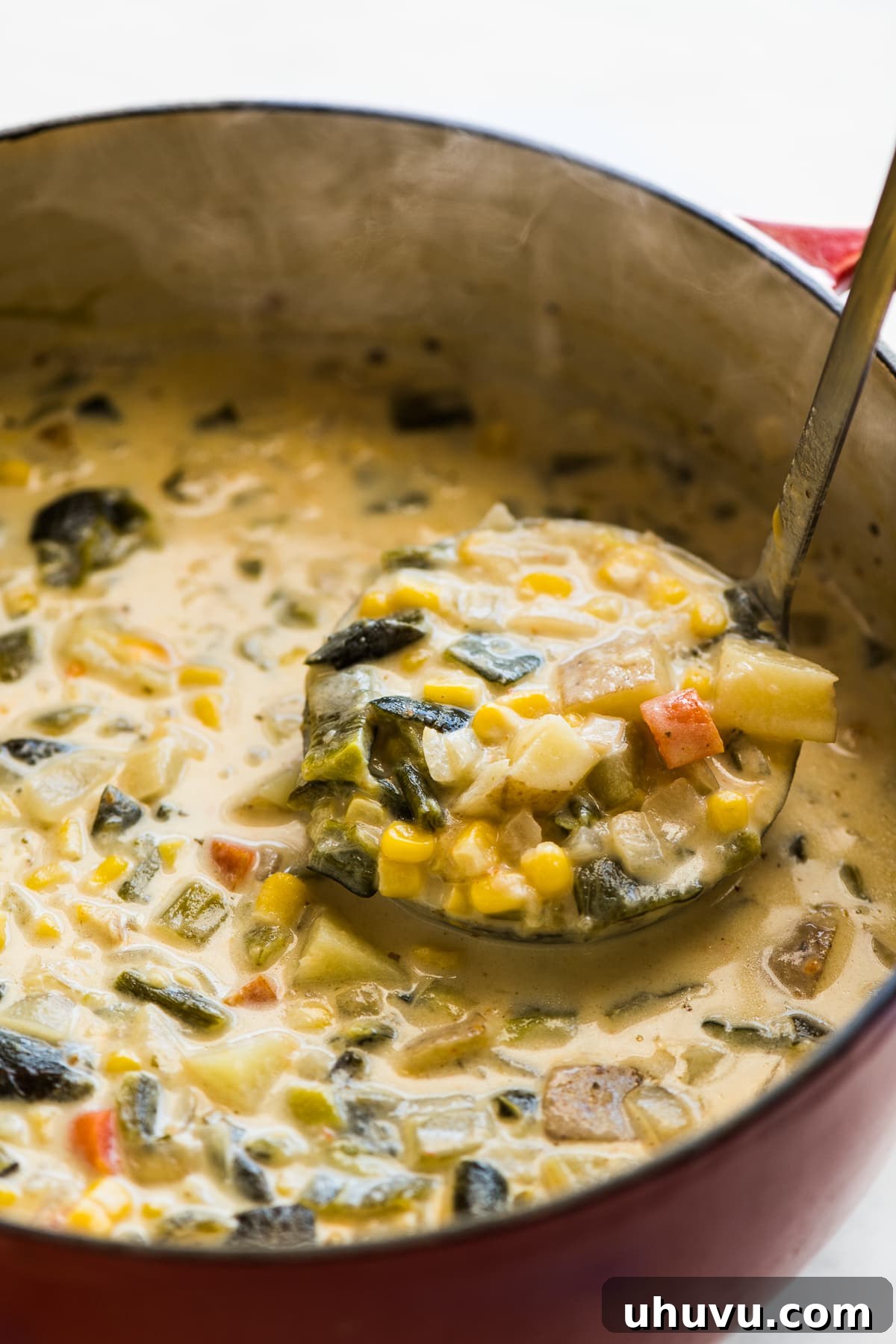 Smoky Roasted Poblano Corn Chowder 6 A ladle serving a generous portion of creamy Roasted Poblano Corn Chowder from a large pot, ready to be enjoyed.