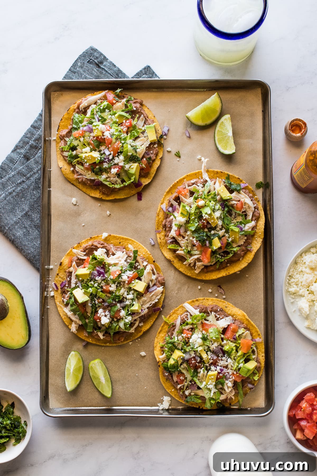 Two vibrant chicken tostadas, layered with refried beans, shredded chicken, and an assortment of fresh toppings including lettuce and salsa.
