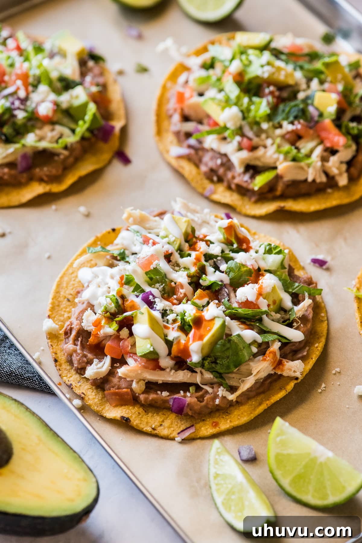 A pair of chicken tostadas, generously topped with sour cream and salsa, showcasing their delicious layers.