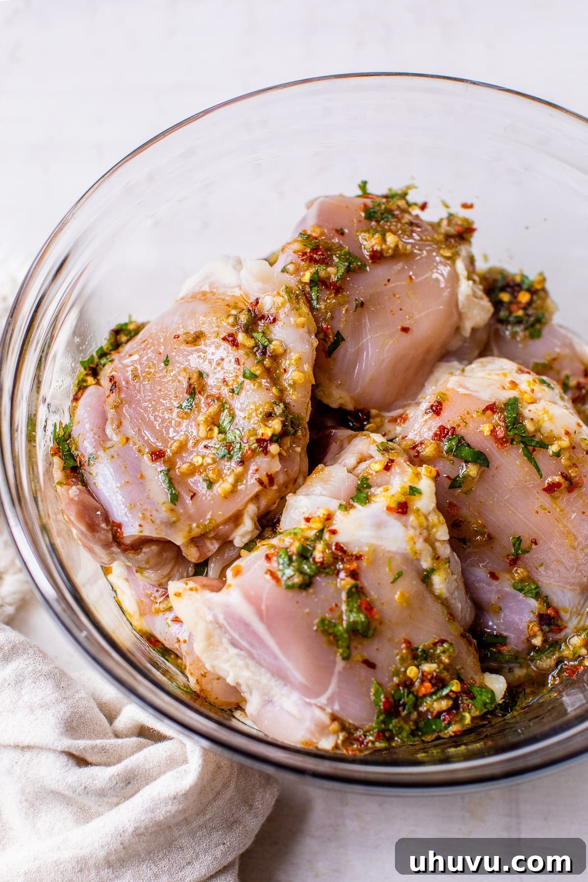Vibrant Lime Chicken Marinade 3 Raw chicken thighs soaking in a bowl filled with vibrant green lime chicken marinade, ready for refrigeration.