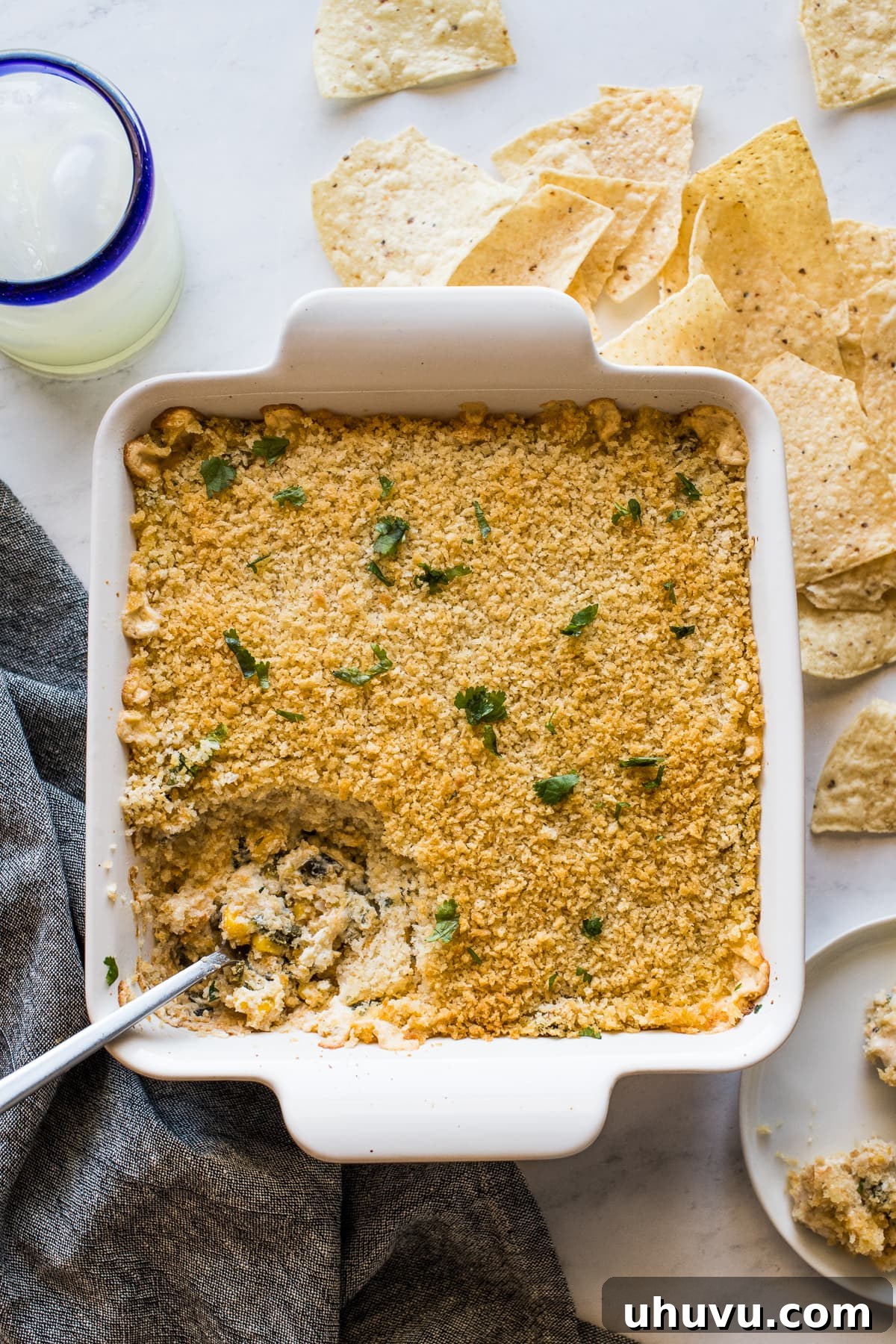 Baked chile relleno dip in a dish surrounded by tortilla chips.