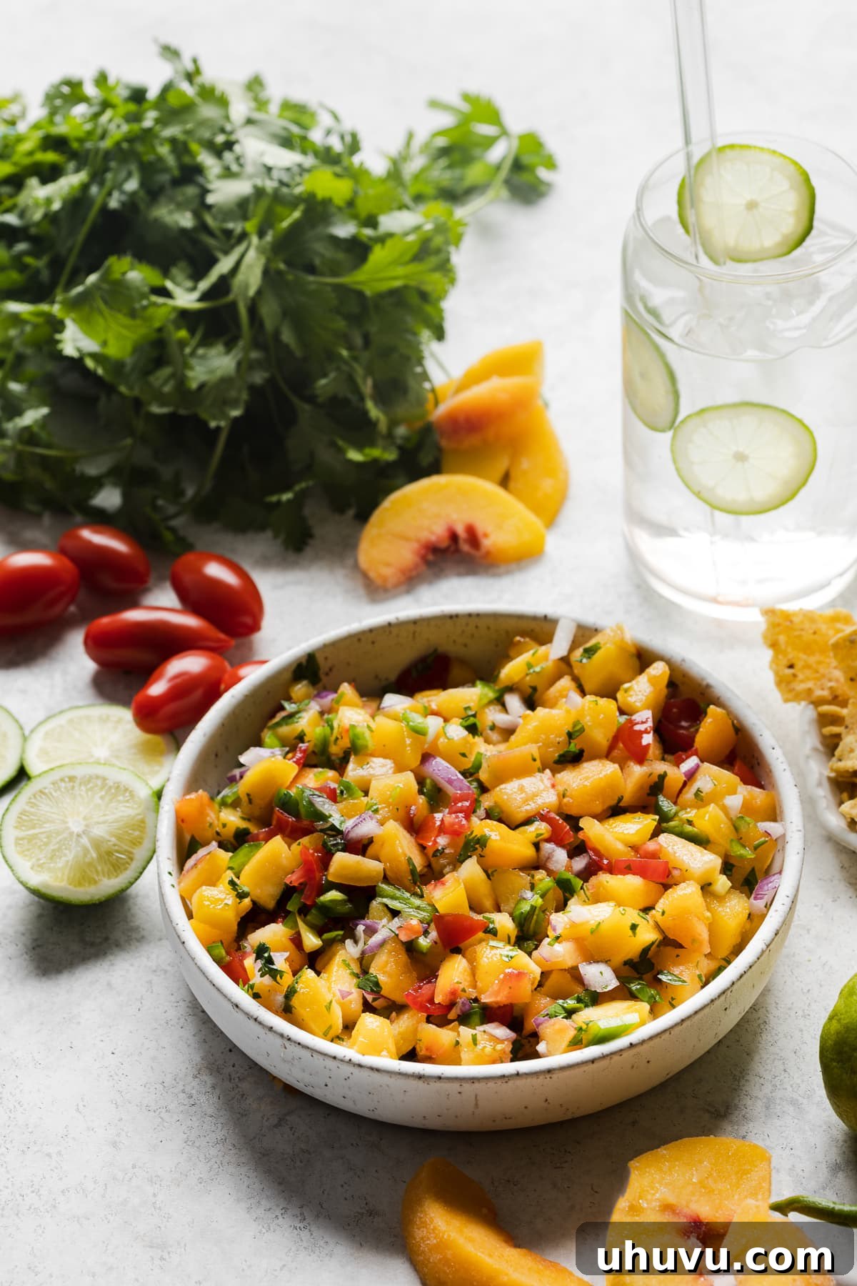 Sunshine Peach Salsa 4 A table with a bowl of peach salsa next to slices of fresh peaches.