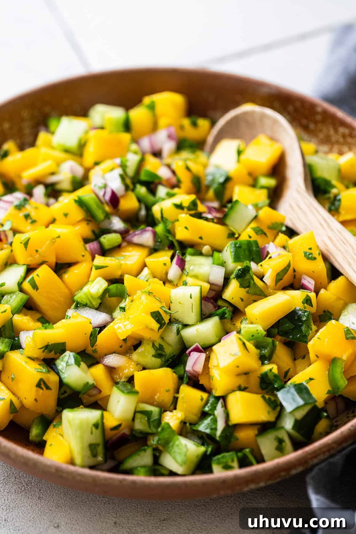 Tropical Mango Medley 6 Close-up of vibrant mango salsa, freshly mixed and ready to serve in a large bowl, garnished with cilantro.