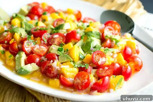 Fresh ingredients for Mango Avocado Salsa, including diced mango, avocado, cherry tomatoes, and red onion