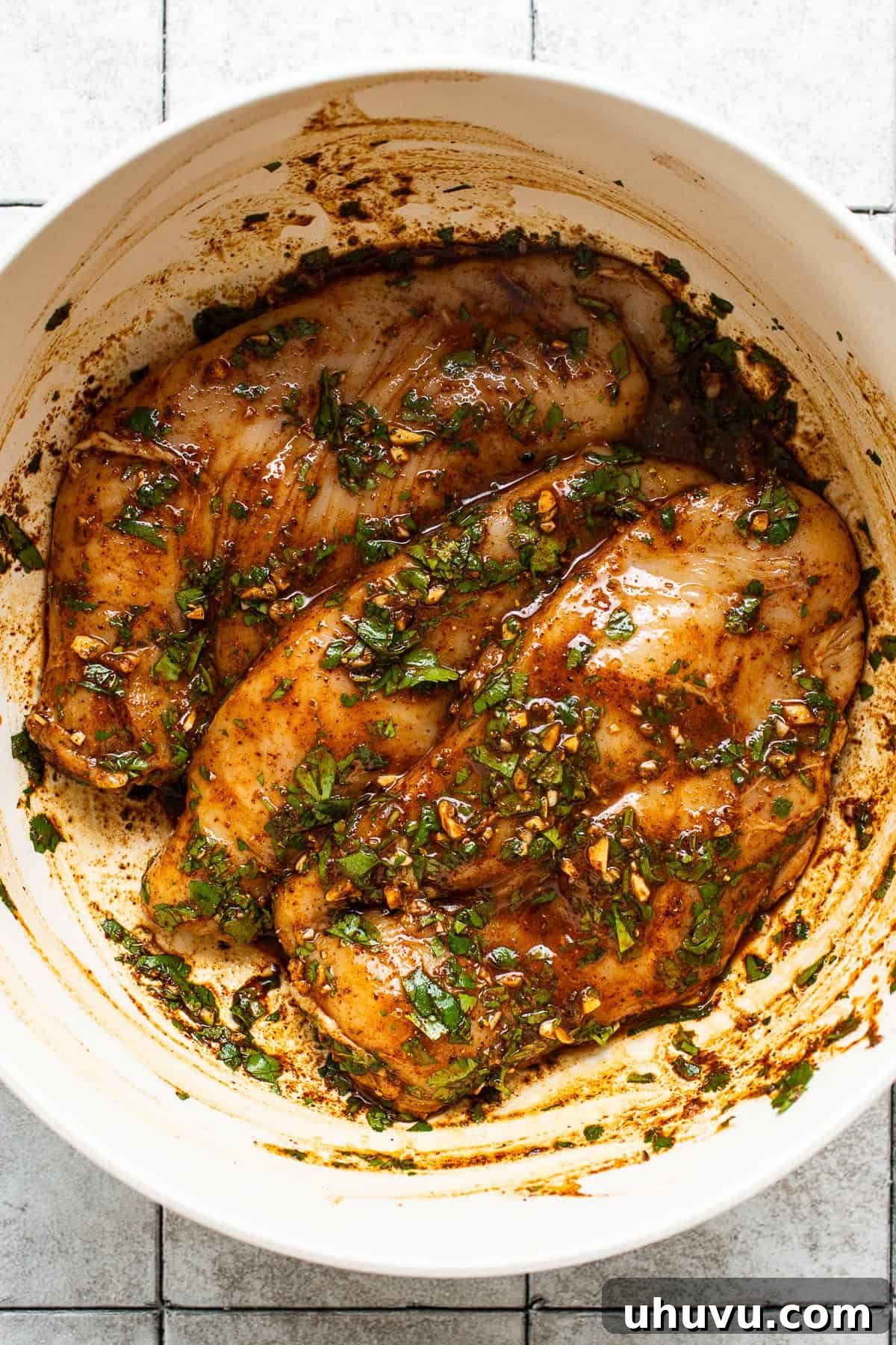 Sizzling Chicken Fajitas 4 Raw chicken breasts generously coated with all the fajita marinade ingredients in a large bowl.