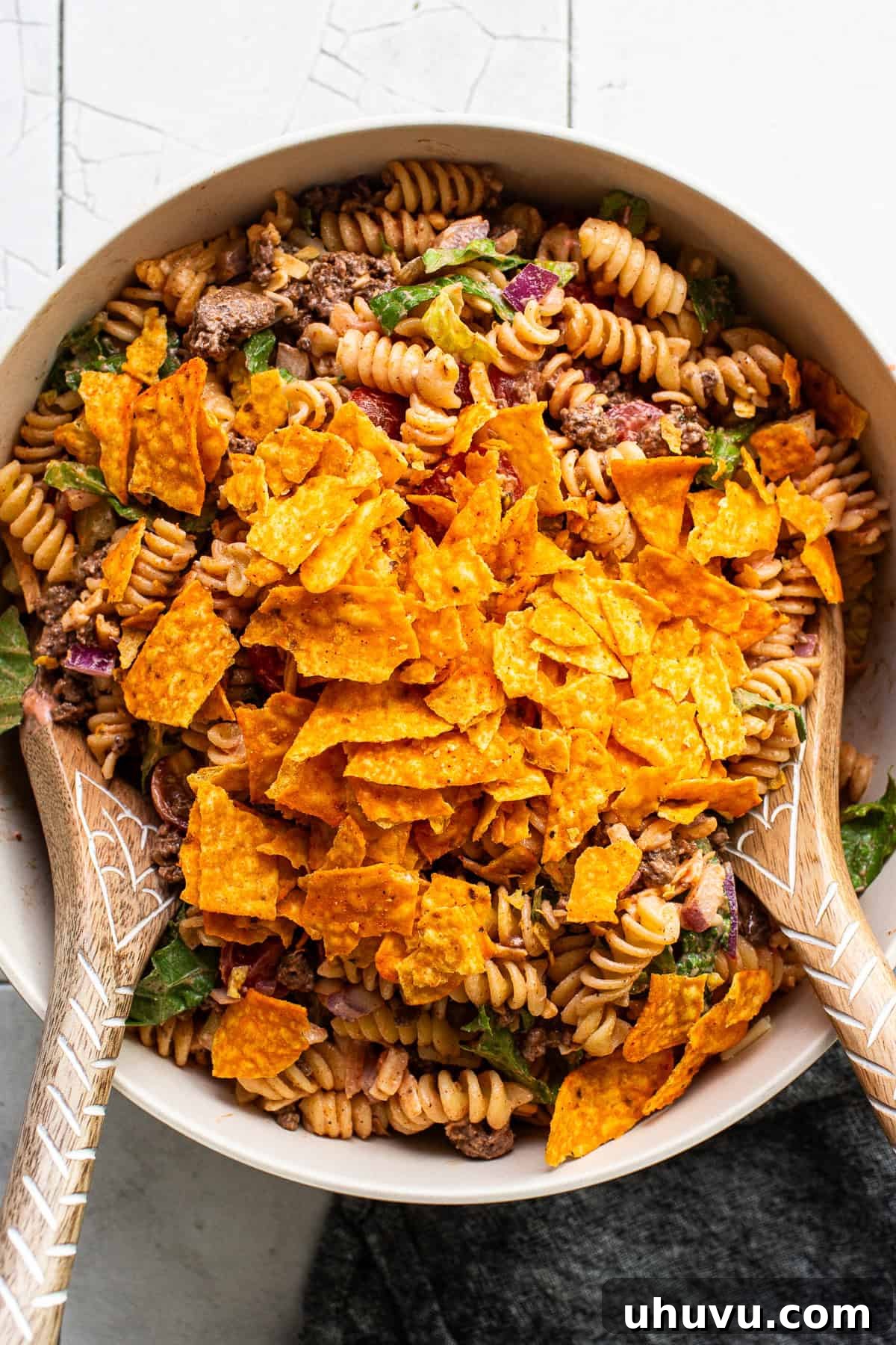 Zesty Taco Pasta Medley 7 Crushed Doritos being sprinkled generously over the top of the prepared taco pasta salad.