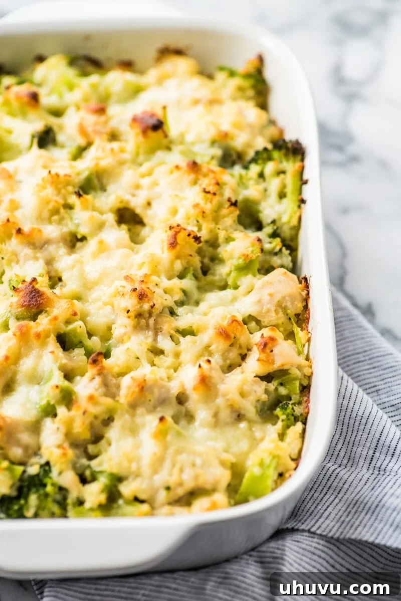 Close-up of the bubbly, golden cheese topping on the low-carb broccoli cauliflower rice chicken casserole, highlighting its appetizing texture.