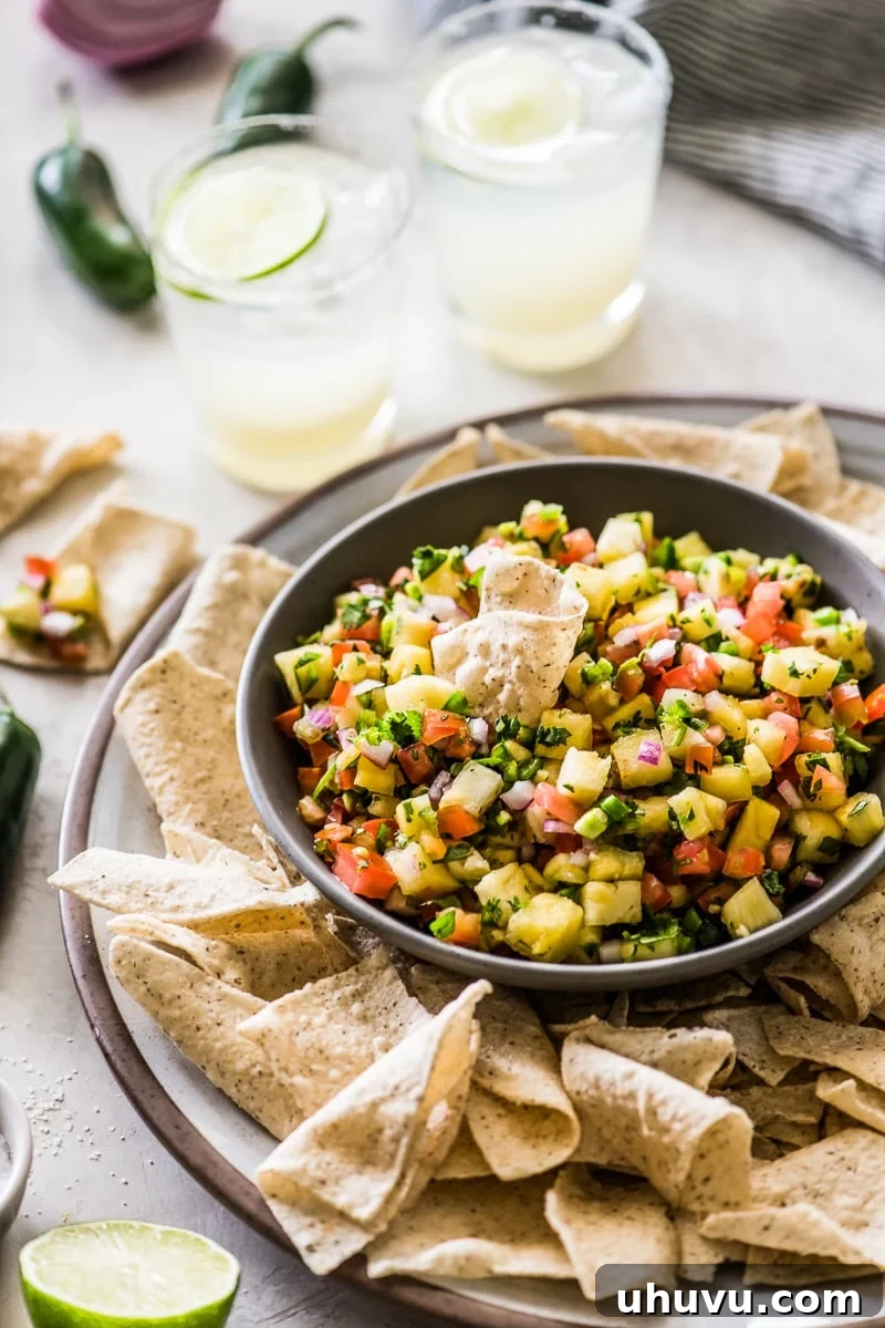 Effortless Pineapple Salsa 5 Pineapple salsa in a bowl with a tortilla chip scooping some out.