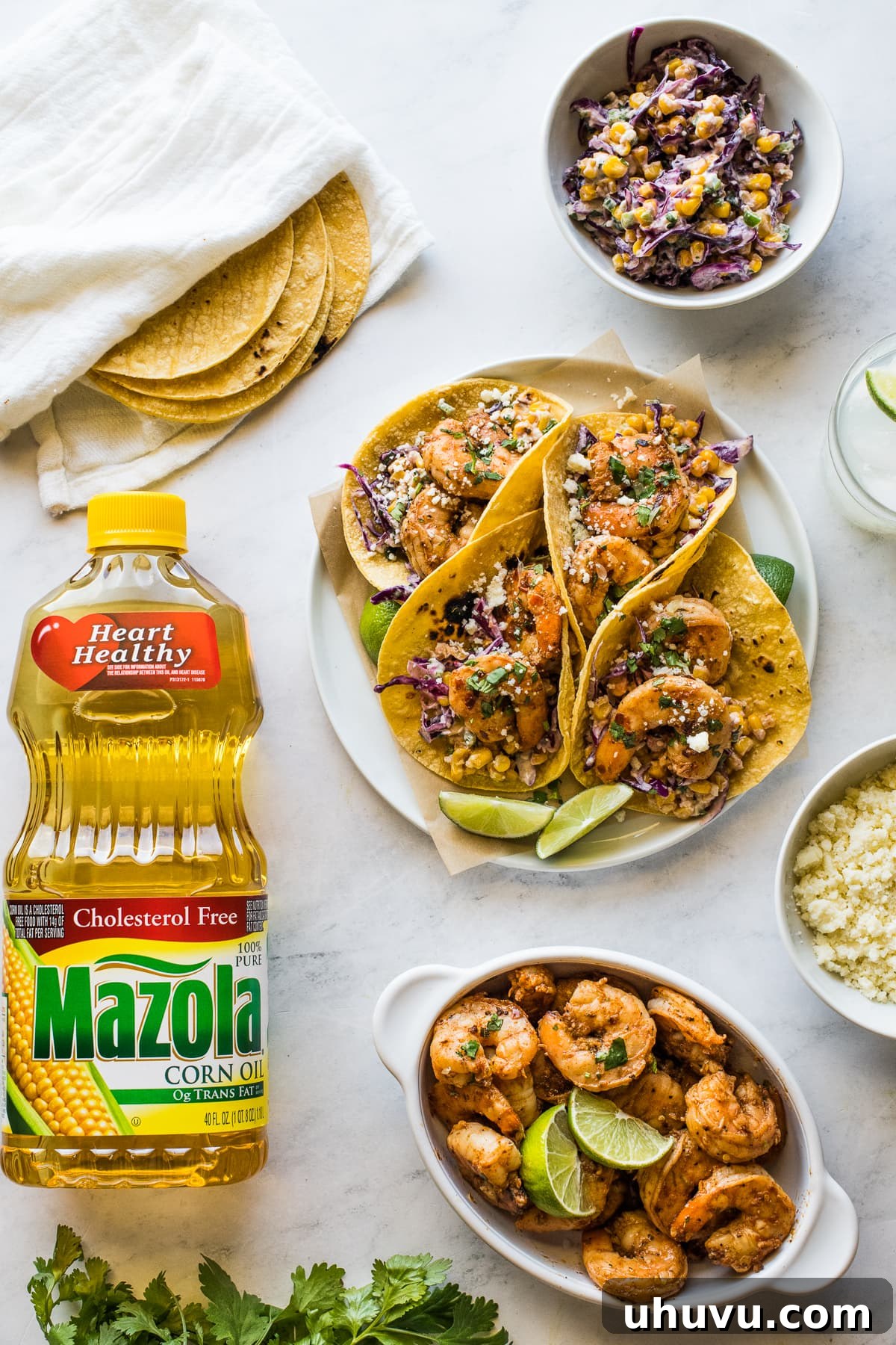 Chili-Lime Shrimp Tacos with Creamy Elote Slaw 2 A plate of spicy shrimp tacos, accompanied by corn tortillas, a vibrant elote slaw, crumbled cotija cheese, and fresh cilantro, showcasing a tantalizing spread for a flavorful meal.