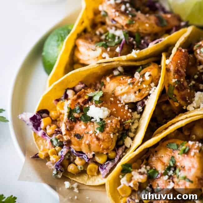 Spicy shrimp tacos, generously topped with fresh cotija cheese and chopped cilantro, presented on a warm tortilla.