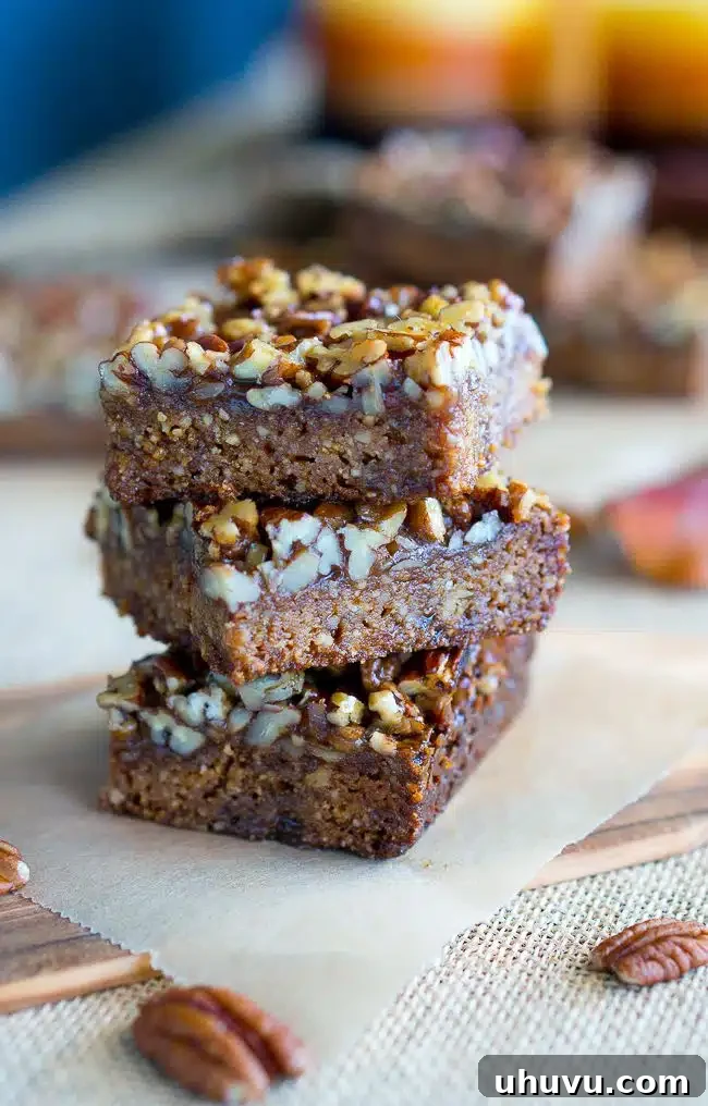 Stacked homemade Paleo Pecan Pie Bars, showing off the thick pecan topping.