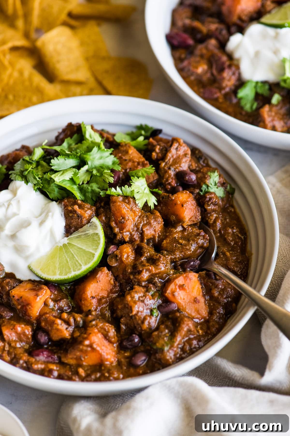 Sweet and Smoky Chipotle Pork Chili 7 A bowl of Chipotle Sweet Potato Pork Chili topped with sour cream, fresh cilantro, and a lime wedge, presented beautifully for serving.