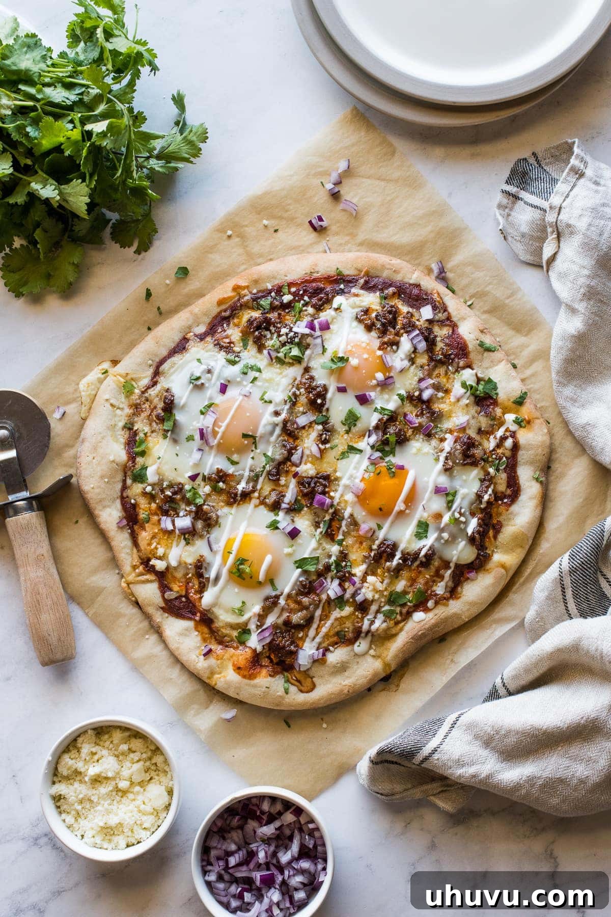 Morning Fiesta Pizza 2 A vibrant Mexican Breakfast Pizza garnished with fresh sour cream, cilantro, and diced red onions, ready to be served.