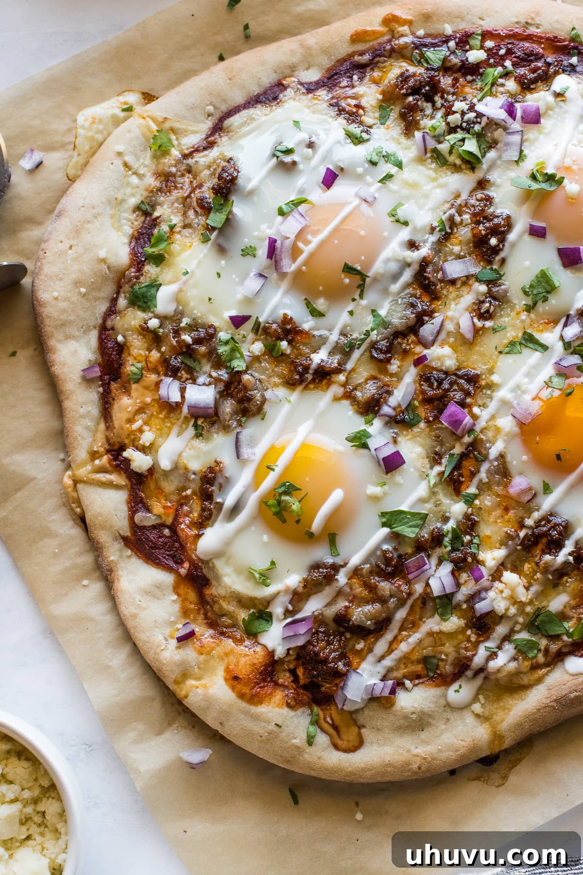 Morning Fiesta Pizza 6 Close-up of a Mexican Breakfast Pizza, freshly baked and topped with a creamy drizzle of sour cream, chopped cilantro, and diced red onions.
