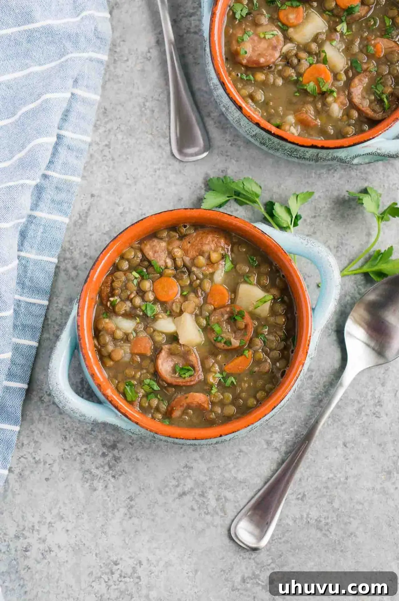 Two cozy bowls of vegetable soup with lentils and sausage, garnished with fresh herbs, perfect for a warming meal.