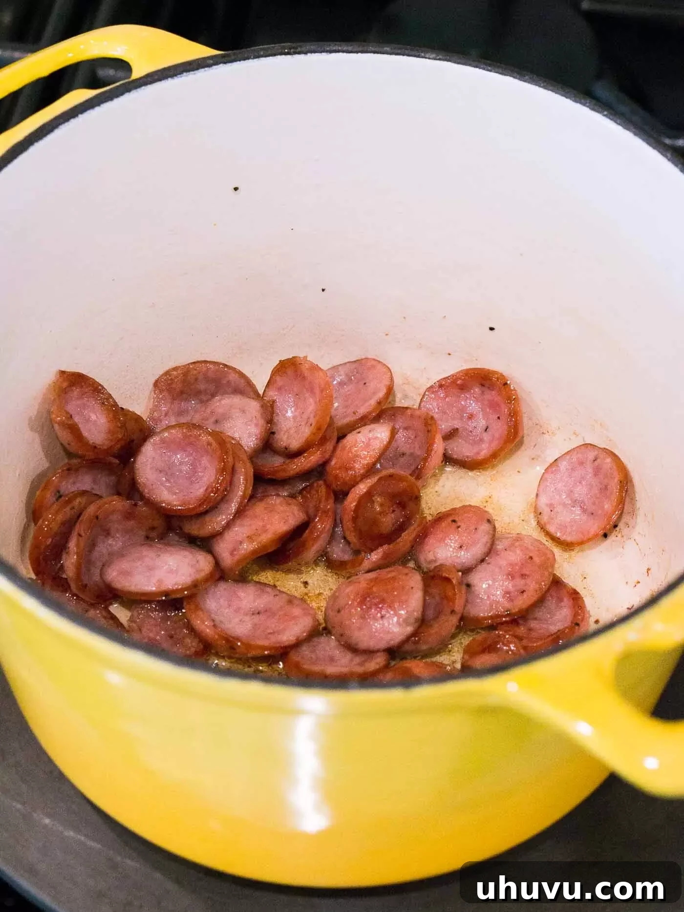 Sausage browning in a large Dutch oven, creating a flavorful base for the lentil soup.