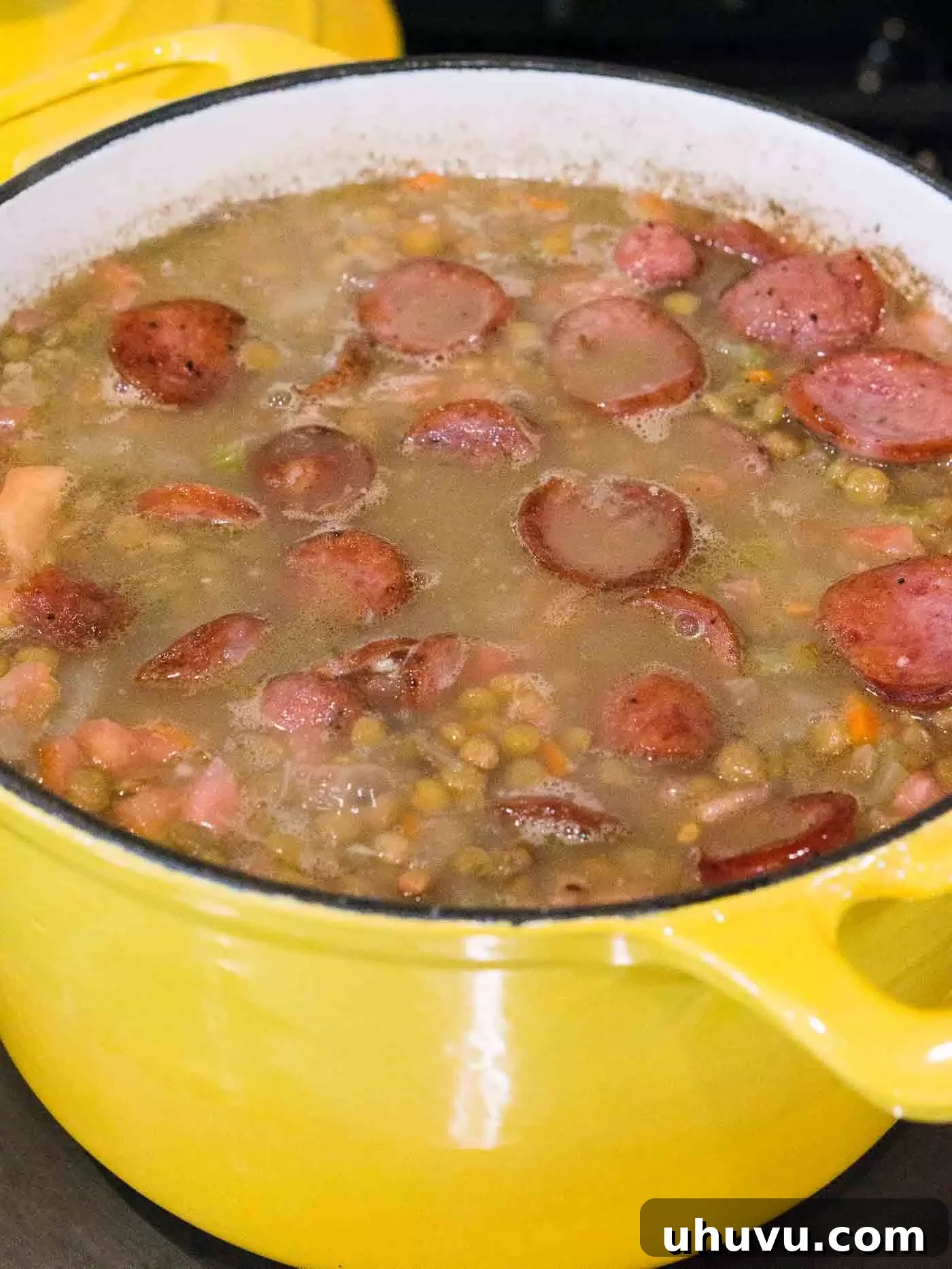 Cooked lentil soup with browned sausage added back in, ready for final seasoning and serving.