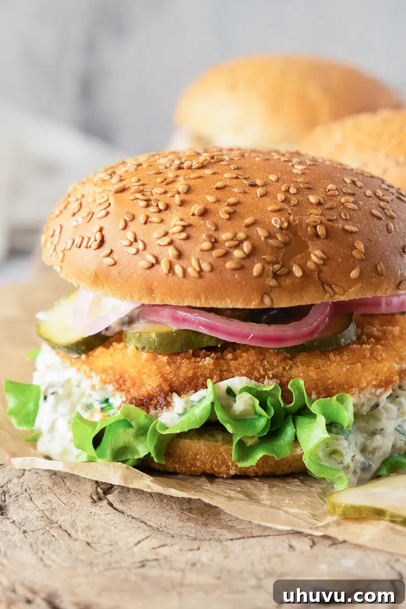 Crispy fish burger with homemade tartar sauce, fresh lettuce, and pickled onions on a bun