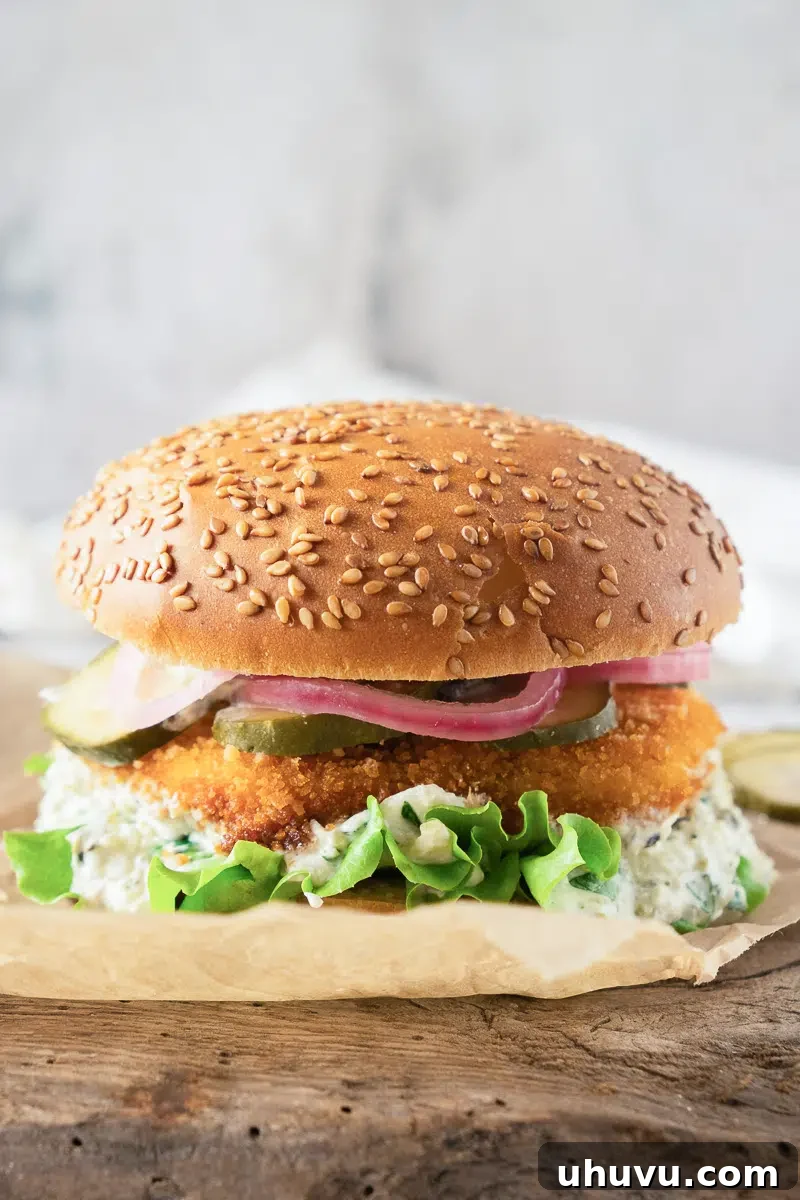 Fish burger served on a rustic wooden board with a side of fries