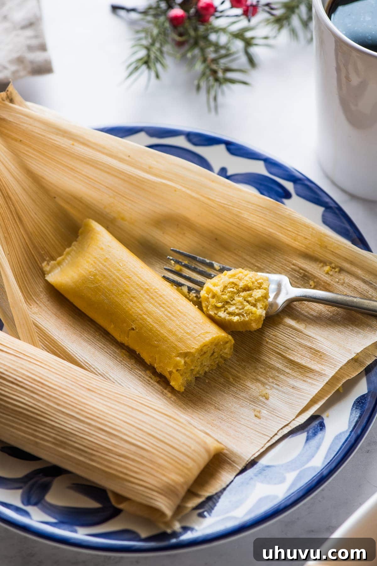 Fresh Corn Tamales 7 A cooked sweet corn tamale on a plate next to a cup of coffee.