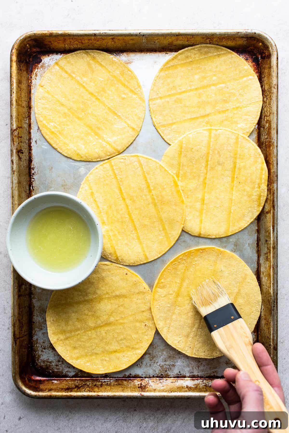 Crispy Oven-Baked Tortilla Chips 4 Oil mixture being brushed onto corn tortillas for baked tortilla chips.