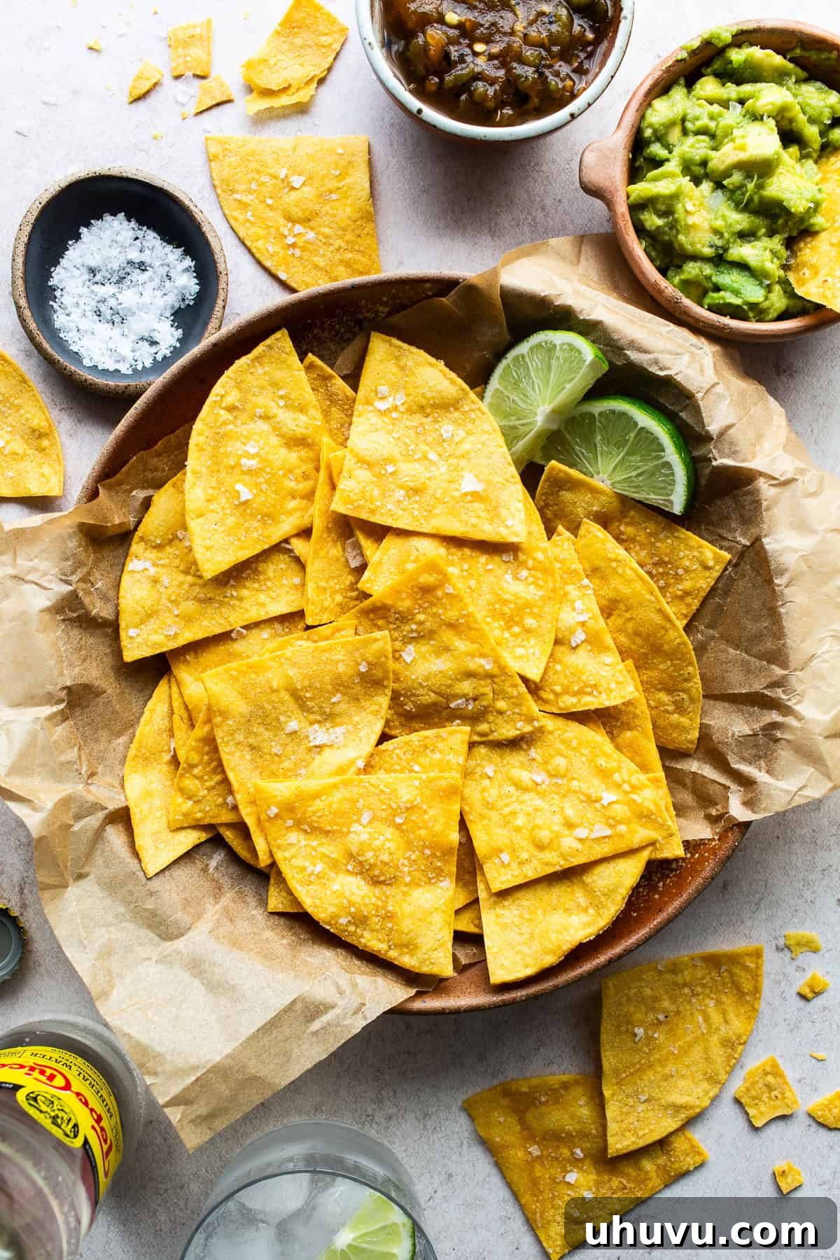 Crispy Oven-Baked Tortilla Chips 7 Crispy baked tortilla chips in a bowl garnished with flaky sea salt and lime wedges for a squeeze of citrus.