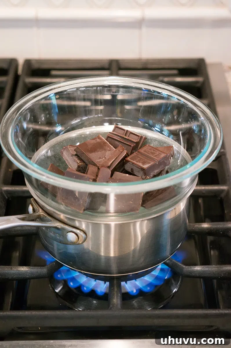 Close-up view of chocolate melting in a double boiler over simmering water on a stove