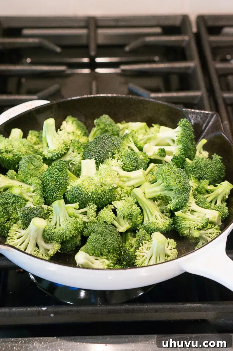 broccoli florets cooking in a skillet on a stovetop