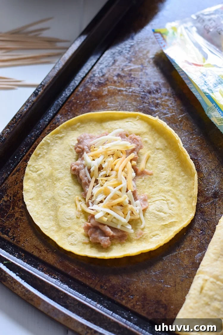 Spreading a layer of mashed pinto beans onto a warm corn tortilla.