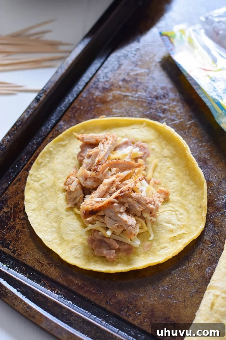 Adding shredded Mexican cheese and seasoned chicken to the tortilla.