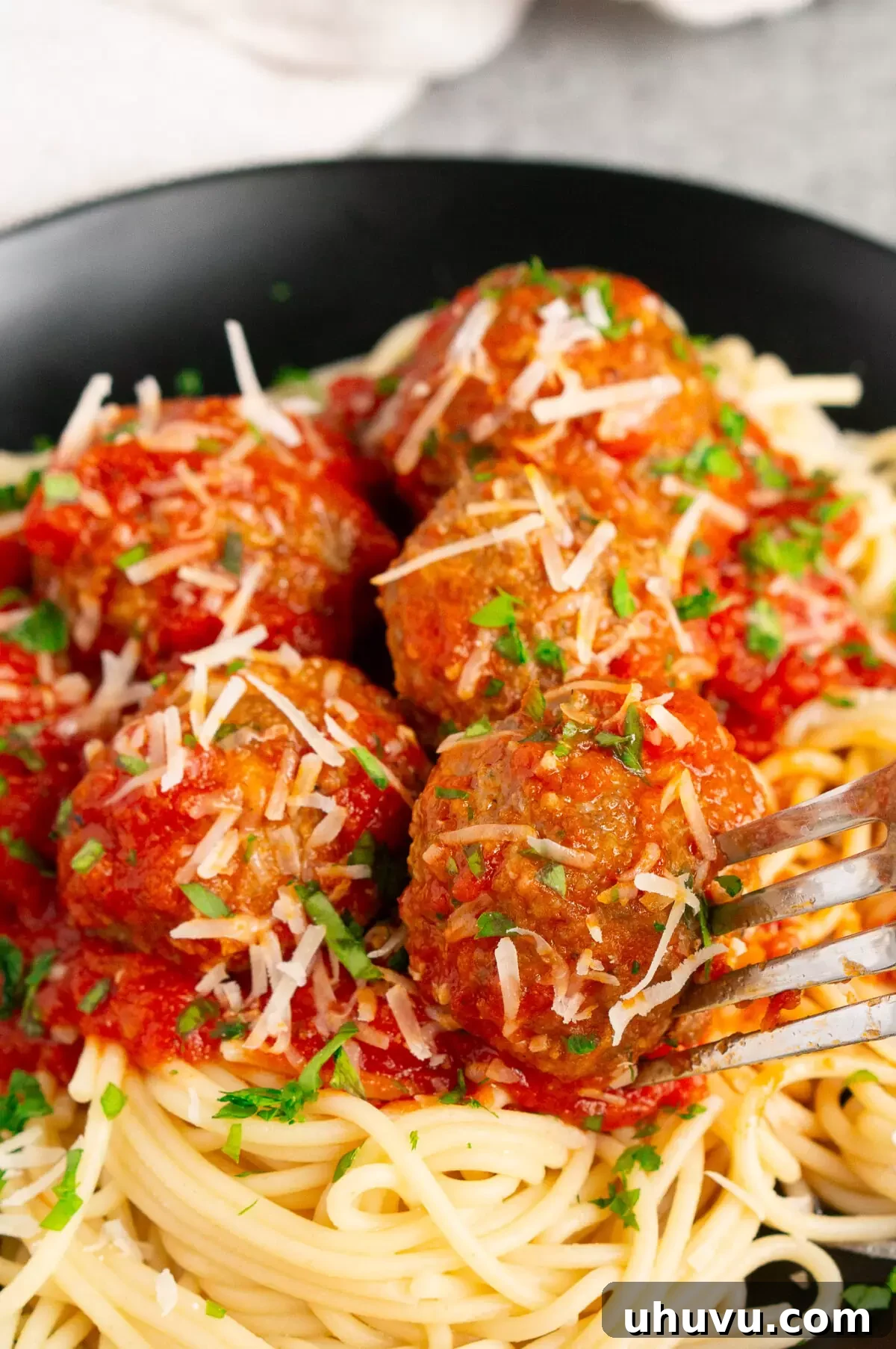 Close-up of baked Italian meatballs in marinara sauce over spaghetti