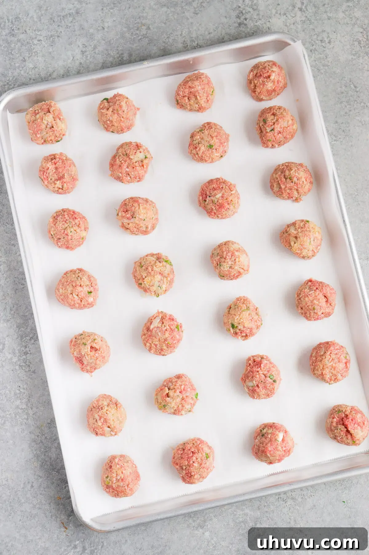 Formed raw Italian meatballs on a baking sheet, ready for the oven