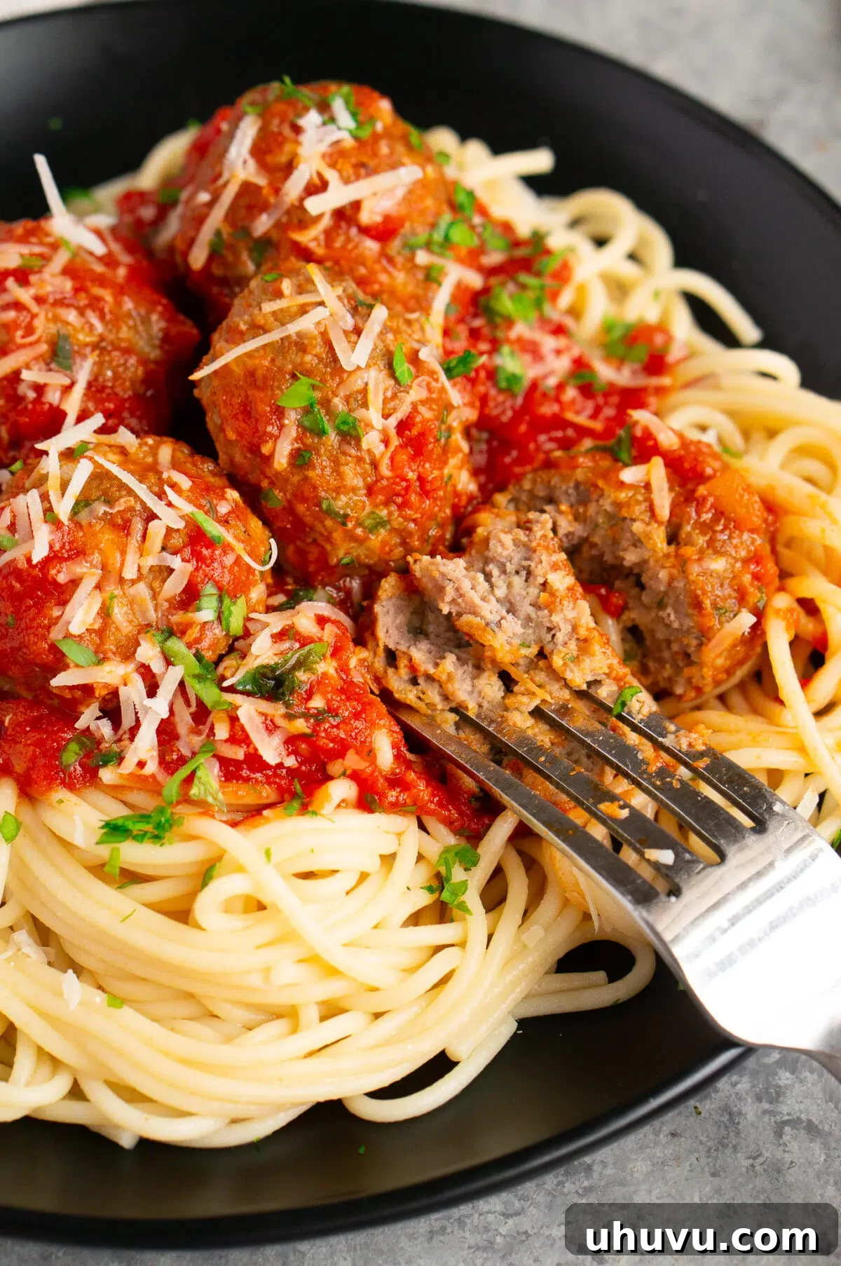 A baked Italian meatball cut in half, showing its tender interior