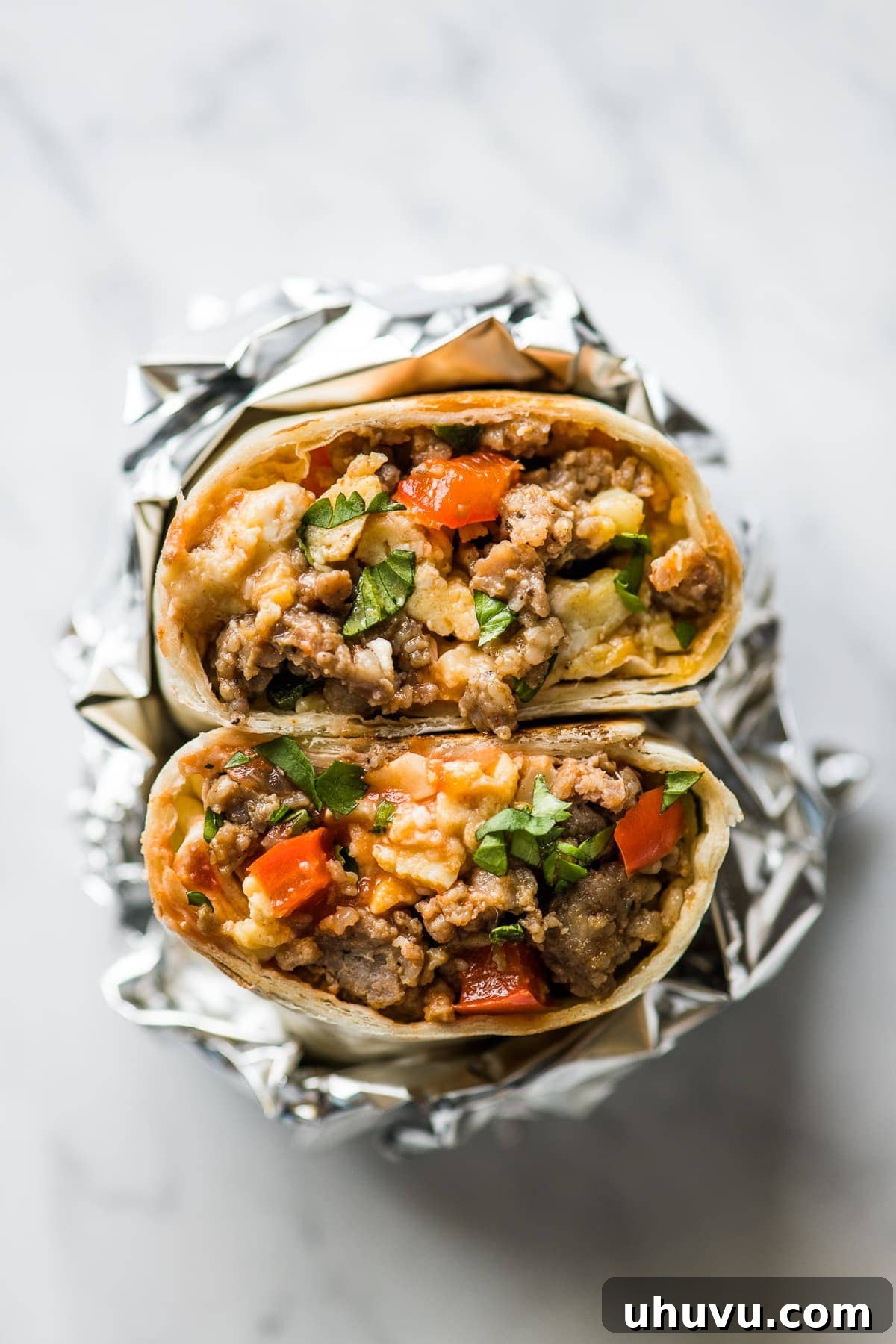 Sunrise Scramble Wraps 2 A breakfast burrito cut in half revealing scrambled eggs, breakfast sausage, melted cheese, and salsa inside.