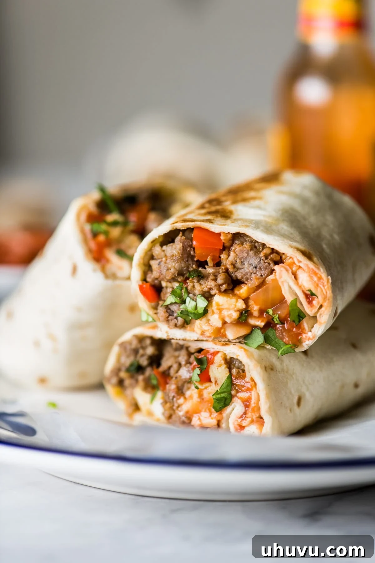 Sunrise Scramble Wraps 5 Breakfast burritos stacked on a plate, showcasing their delicious fillings and golden-brown tortillas.