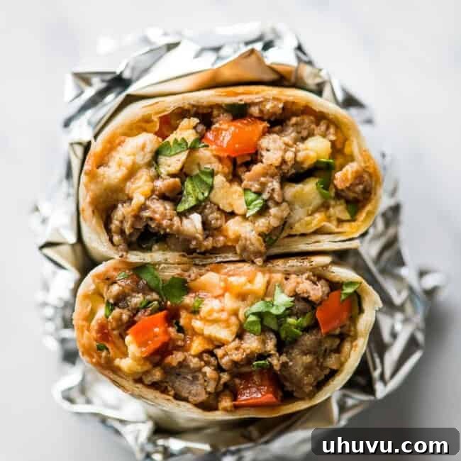 A breakfast burrito cut in half made with scrambled eggs and breakfast sausage.