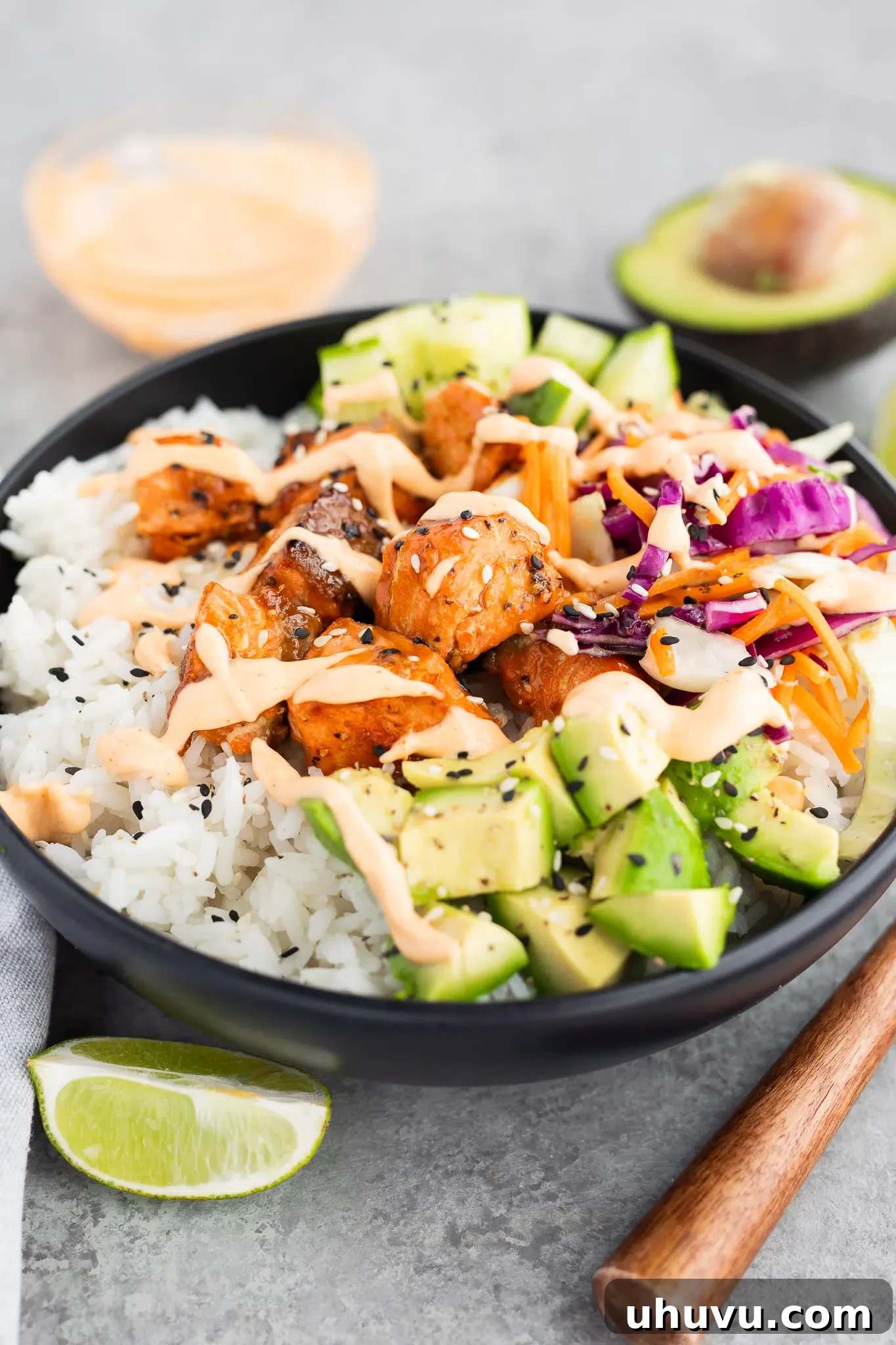 Two beautifully arranged salmon rice bowls with fresh cucumbers and creamy avocados.