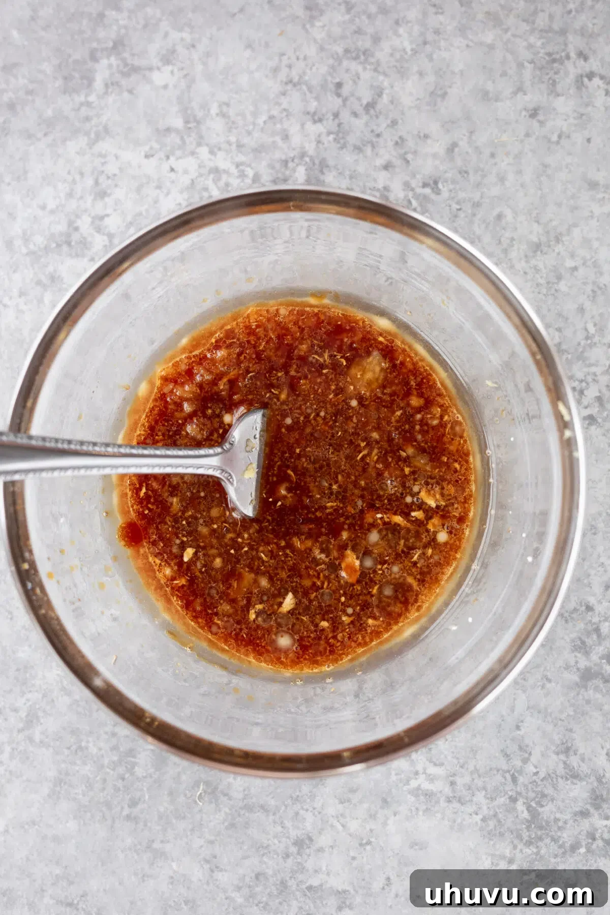 Whisking the homemade teriyaki-style salmon sauce in a small bowl.