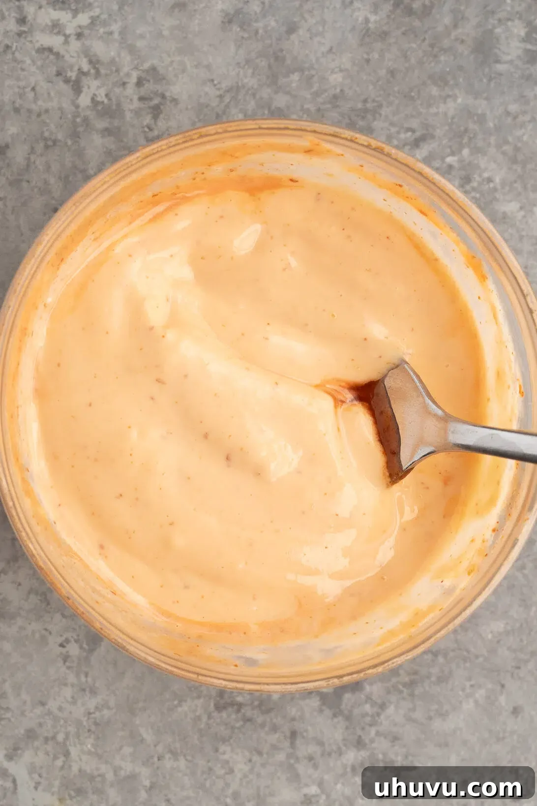 Mixing creamy mayonnaise with spicy sriracha to create the delicious sauce.
