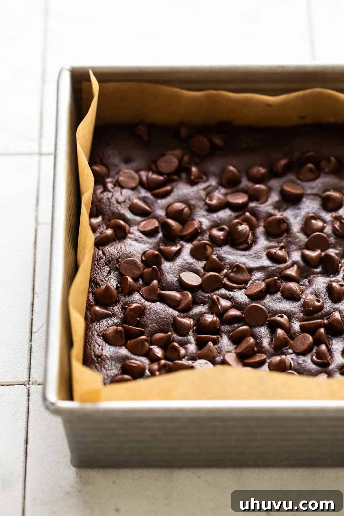 Wholesome Fudgy Black Bean Brownies 8 A freshly baked batch of black bean brownies resting in the pan, their fudgy tops glistening with melted chocolate chips, patiently waiting to be cut and served.
