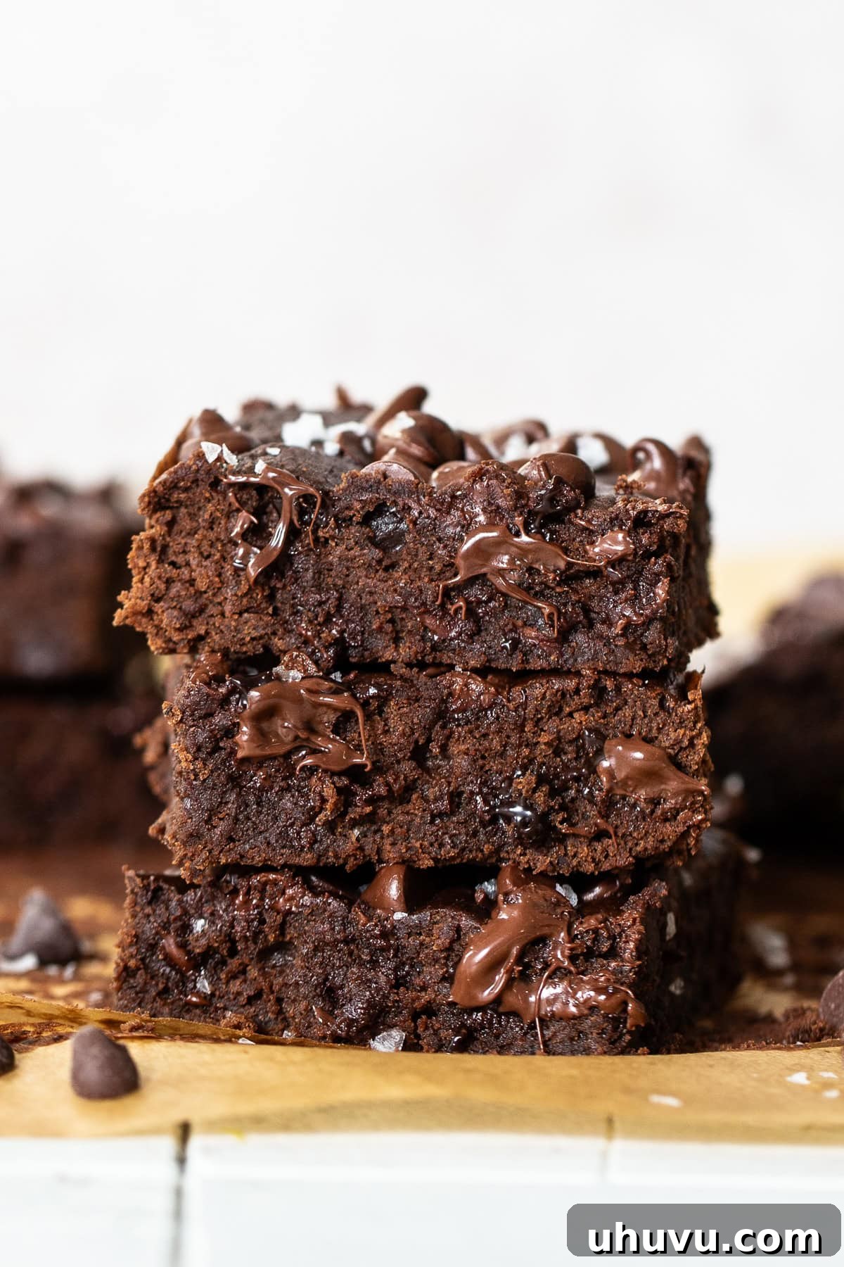 Wholesome Fudgy Black Bean Brownies 9 Three perfectly stacked black bean brownies revealing their gloriously gooey, melted chocolate chip centers, showcasing their rich, fudgy texture and inviting indulgence.